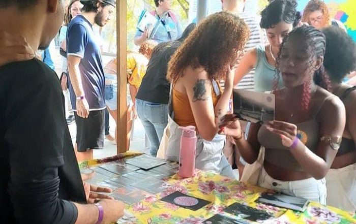 Menina em uma barraca segura um cartão com uma imagem e um texto no verso