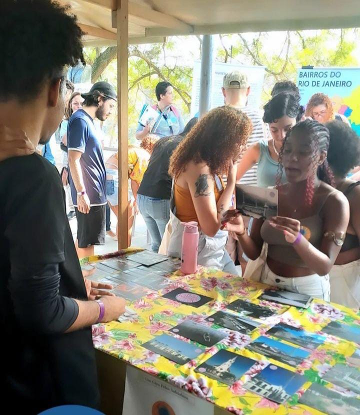 Menina em uma barraca segura um cartão com uma imagem e um texto no verso